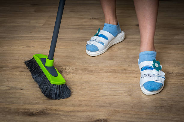 istock Woman with broom sweeping wooden laminate floor 592403674