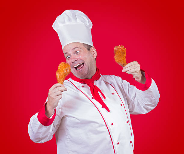 chef holding in his hands a chicken thigh on red background