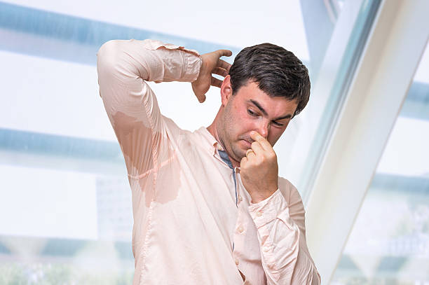istock Man with sweating under armpit pinches nose with fingers 592408772