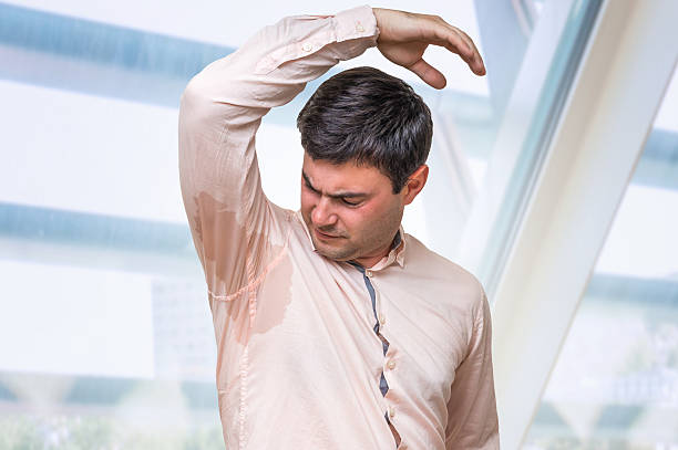 mann mit hyperhidrose schwitzt unter achselhöhle im büro - facial expression unpleasant smell shirt caucasian stock-fotos und bilder