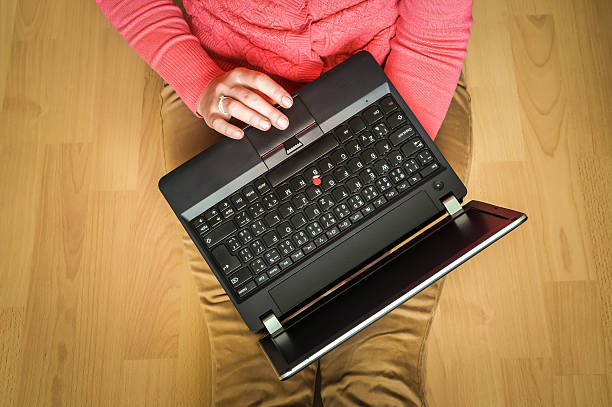istock Young student using laptop and sitting on the wooden floor 592408926