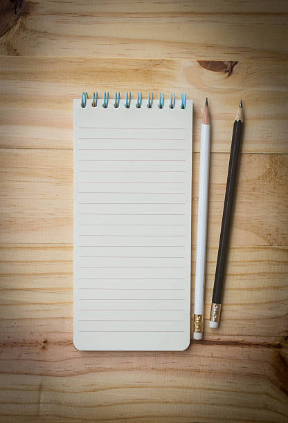istock Notebook and pencils on wooden background , top view 592644696
