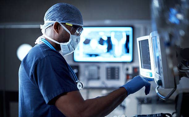 Vigilantly monitoring his patient's vitals Shot of a surgeon looking at a monitor in an operating room paramedic photos stock pictures, royalty-free photos & images