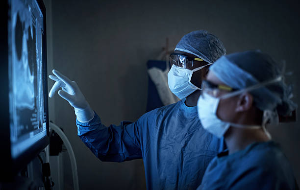 Surgical excellence at it’s best Shot of two surgeons analyzing a patient’s medical scans during surgery operating stock pictures, royalty-free photos & images