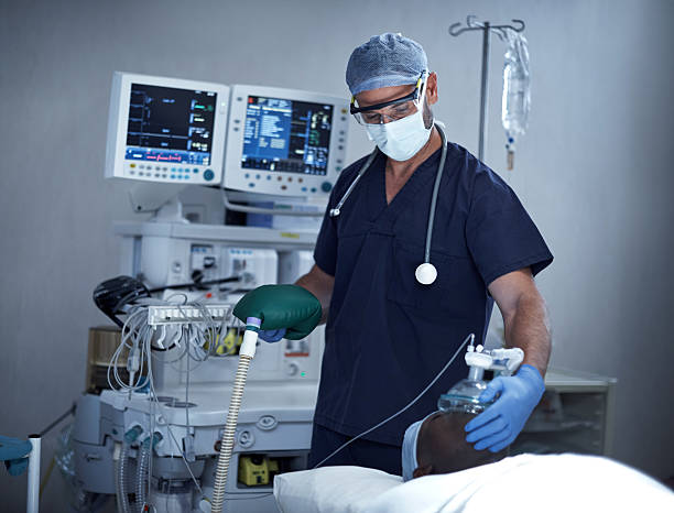 Helping him to breathe Shot of a surgeon using an oxygen mask on a patient during surgery anaesthetist stock pictures, royalty-free photos & images