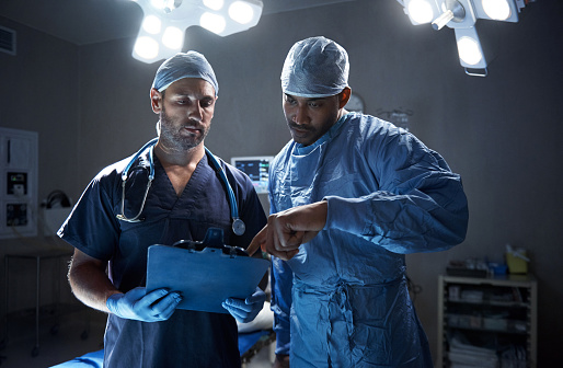 Shot of two surgeons looking at a patient’s file in an operating room