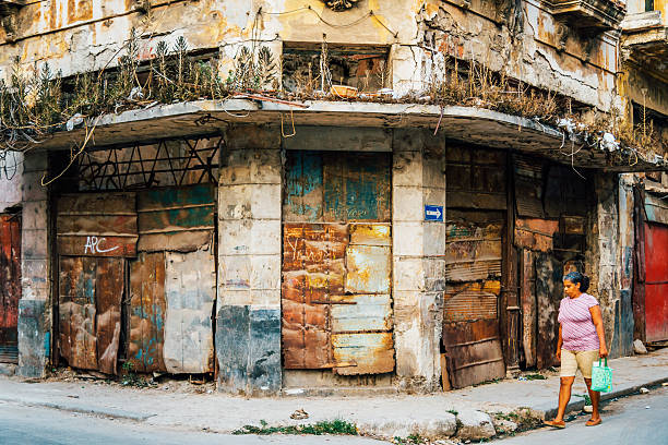 Havana, Cuba - March 19, 2015: Looking down a street in old town Havana with rundown buildings,  a woman with shopping bag crossing street.