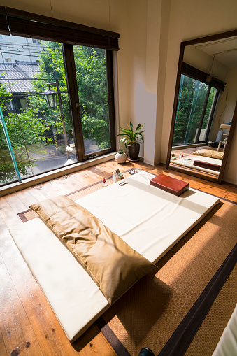 Traditional small Acupuncture studio with tatami in Kyoto, Japan. There is mirror and big window with view of neighboring trees and house on opposite side of street.