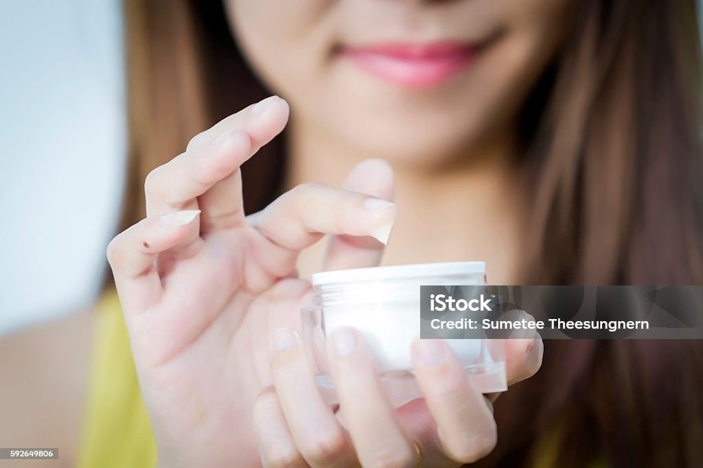 beautiful woman asia using a skin care product, moisturizer or A beautiful woman asia using a skin care product, moisturizer or lotion and Skincare  taking care of her dry complexion. Moisturizing cream in female hands . Adult Stock Photo