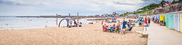 seaside holiday makers beside colourful beach huts lyme regis dorset - family child crowd british culture imagens e fotografias de stock