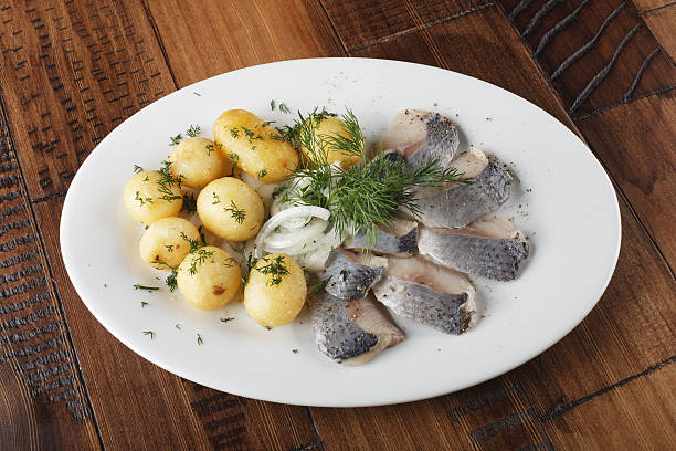 Herring fish with young potato Herring fish with young potato on white plate. wooden background. chopped dill stock pictures, royalty-free photos & images