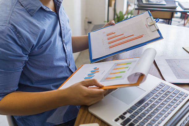 Employee trying to compare data between two charts on folder stock photo