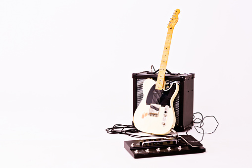 Cape Town, South Africa - July 2, 2016: A Telecaster Thinline electric guitar manufactured by Squier, a budget brand owned by the Fender Musical Instrument Corporation. This instrument is part of Squier's Vintage Modified series, a line introduced in the 2000s to good reviews for its price:performance ratio. This example was made in Indonesia in 2014, and is an authorized reproduction of the semi-hollow Fender Telecaster Thinline model introduced in 1972, sporting humbucking pickups, a novelty for Fender at the time. The guitar is leaning against a Roland Cube 80GX amplifier, with a multi-effects unit in the foreground. Ample copy space to the left.
