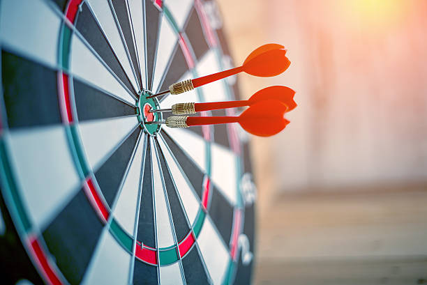 red dart arrow hitting in the target center - dartboard imagens e fotografias de stock