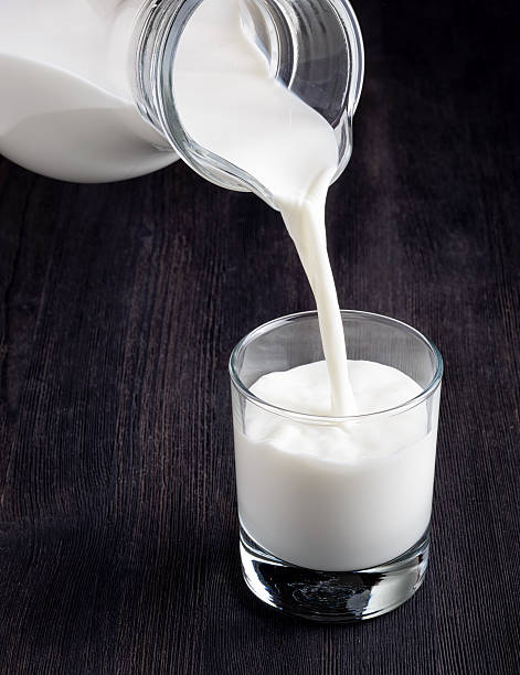 istock Milk pouring into a glass on black board 592659990