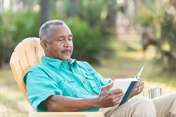 senior black man lettura libro all'aperto - men reading outdoors book foto e immagini stock