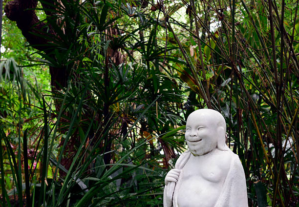 Profile of a Happy Buddha in Asian garden. Profile of a Happy Buddha in Asian garden at Nature Coast Botanical Garden in Spring Hill, Florida. laughing buddha garden statue stock pictures, royalty-free photos & images