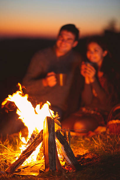 istock Happy couple sitting by fire on autumn beach 592666110