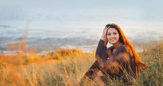 Portrait of the beautiful brunette woman at the windy autumn day relaxing on coast feeling good