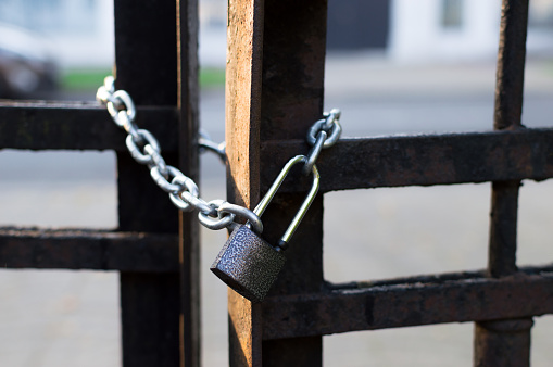 Chain and lock on the iron fence. Closeup view. Sharp lock. Blur background. Black and white