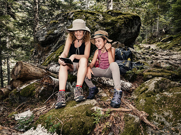 istock Mother and daughter watching smartphone in forest 592672688