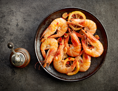 plate of fried spiced prawns on dark table, top view