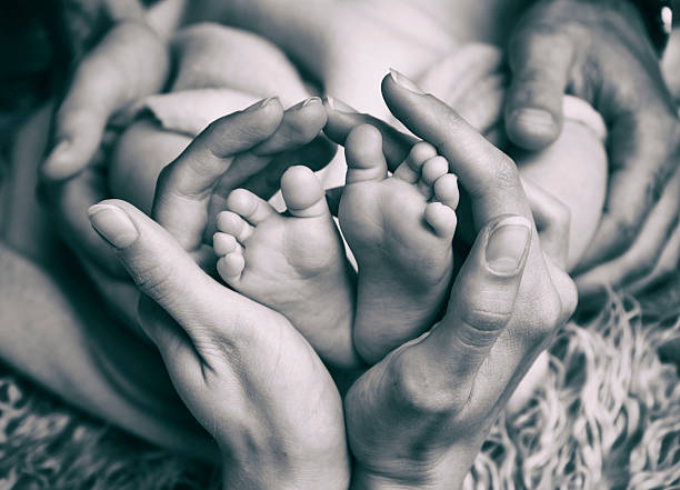 madre sosteniendo tiernamente los pies de sus bebés - barefoot behavior toned image close up fotografías e imágenes de stock