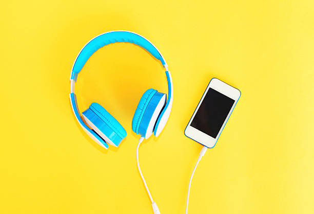 istock Headphones connected to white smartphone over yellow background 592674848