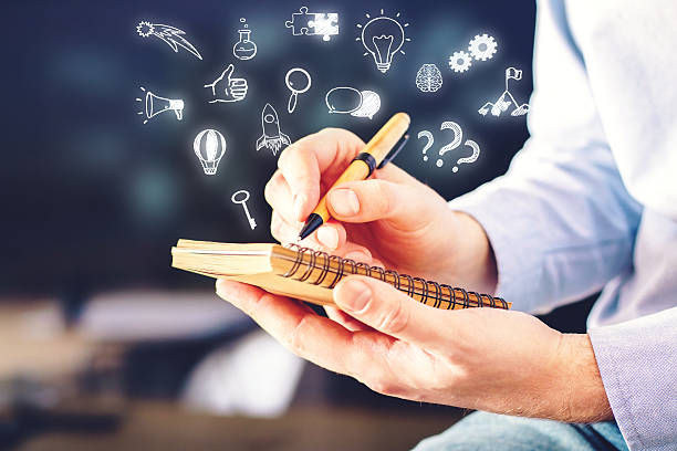 Businessman holding spiral notepad with abstract business icons on blurry background