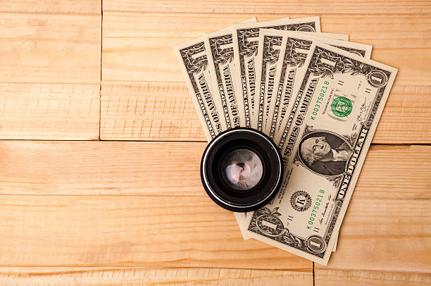 Photo lens with money on wooden background. Buying expensive photographic stock photo