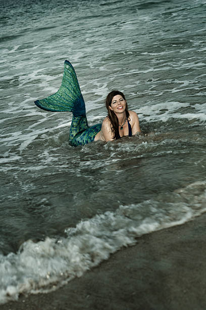 istock Happy mermaid with green tail in ocean 592686578