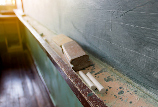 two chalk sticks in chalkboard track in classroom