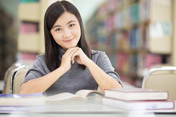 istock Woman reading a book in library 592688986