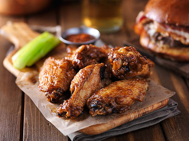 crispy barbecue chicken wings with celery crispy barbecue chicken wings with celery on wooden serving tray pub food stock pictures, royalty-free photos & images