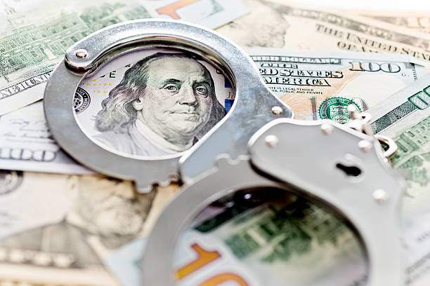 Handcuffs lying on american dollars Handcuffs lying on american dollars, financial crime concept. crime stock pictures, royalty-free photos & images