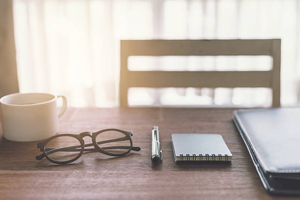 istock Notebook and cup of coffee with sunlight on desk office 593299352