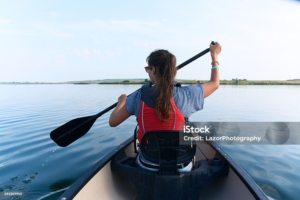 Mujer joven en canoa en el lago en un día de verano. - Foto de stock de Canoa libre de derechos