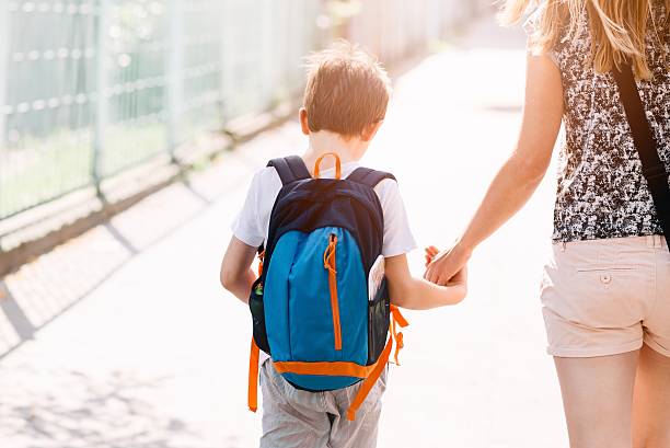 istock 7 years old boy going to school with his mother 593302288