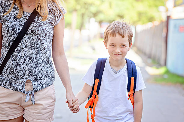 istock 7 years old boy going to school with his mother 593302466