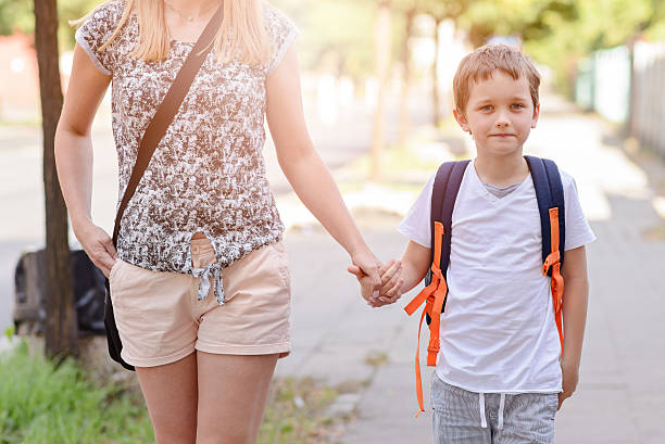istock 7 years old boy going to school with his mother 593302628