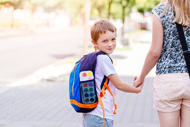 istock 7 years old boy going to school with his mother 593302772
