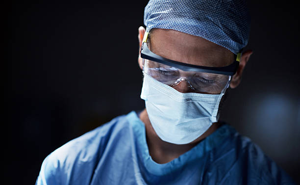 I'm making a positive contribution to my community and society Shot of a surgeon in an operating room protective eyewear stock pictures, royalty-free photos & images