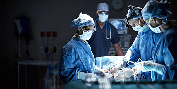 Putting their skills to good use Shot of a team of surgeons performing a surgery in an operating room surgeon stock pictures, royalty-free photos & images