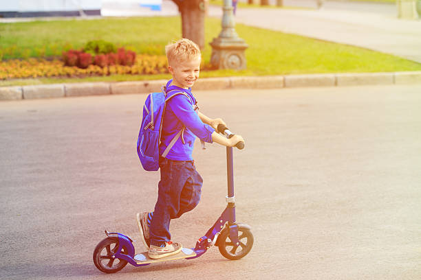 istock little boy riding scooter in the city 593306306