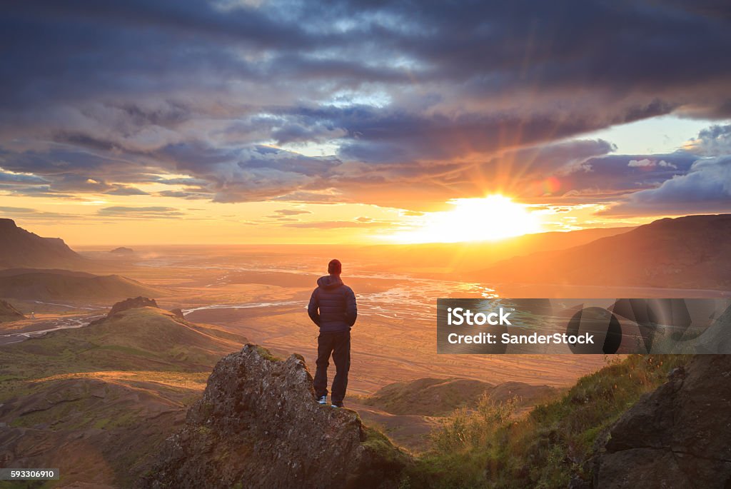 Iceland sunset Man standing on a ledge of a mountain, enjoying the sunset over a river valley in Thorsmork, Iceland.  Men Stock Photo