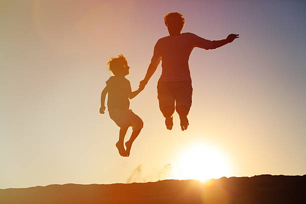 istock father and son jumping at sunset 593309194