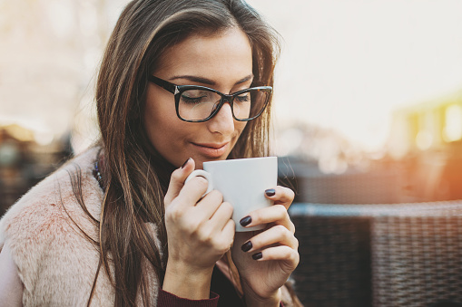 Young woman holding a cup of coffee, taking the aroma, with copy space