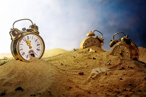 sand running out of a nostalgic alarm clock, other watches sink into the sand, surreal metaphor in a fantasy landscape, concept of time passes by, eventide or infinity, selected focus, very shallow depth of field