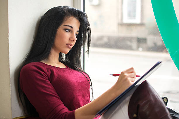 istock Female student studying for college exam near the window. 593319010