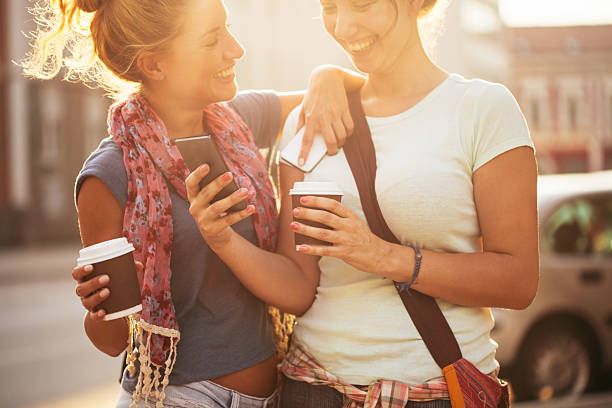 istock Happy female friends reading a text message outdoors 593322208